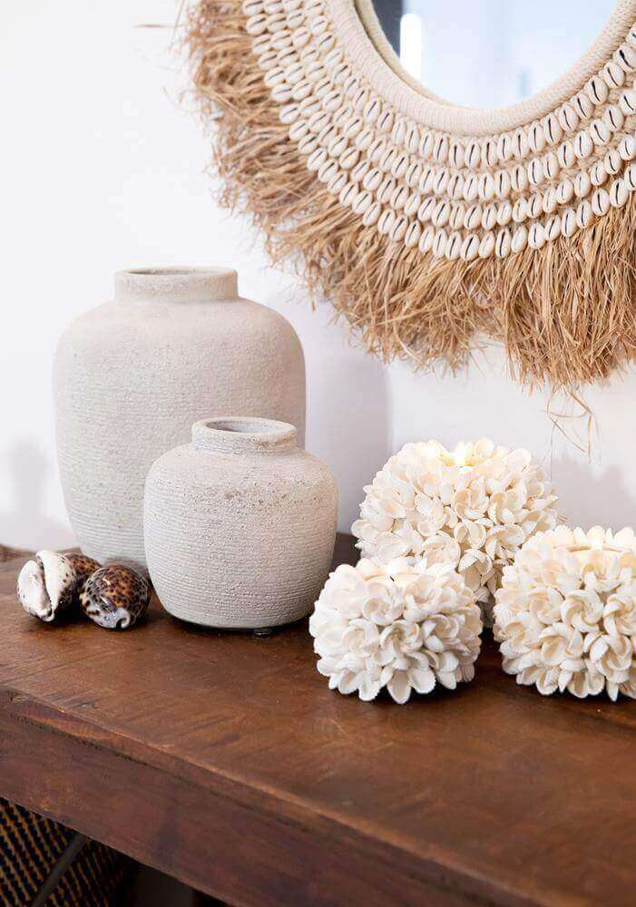 Boho spiegel met raffia en schelpen, rustiek interieur met decoratieve vazen en kustaccenten.