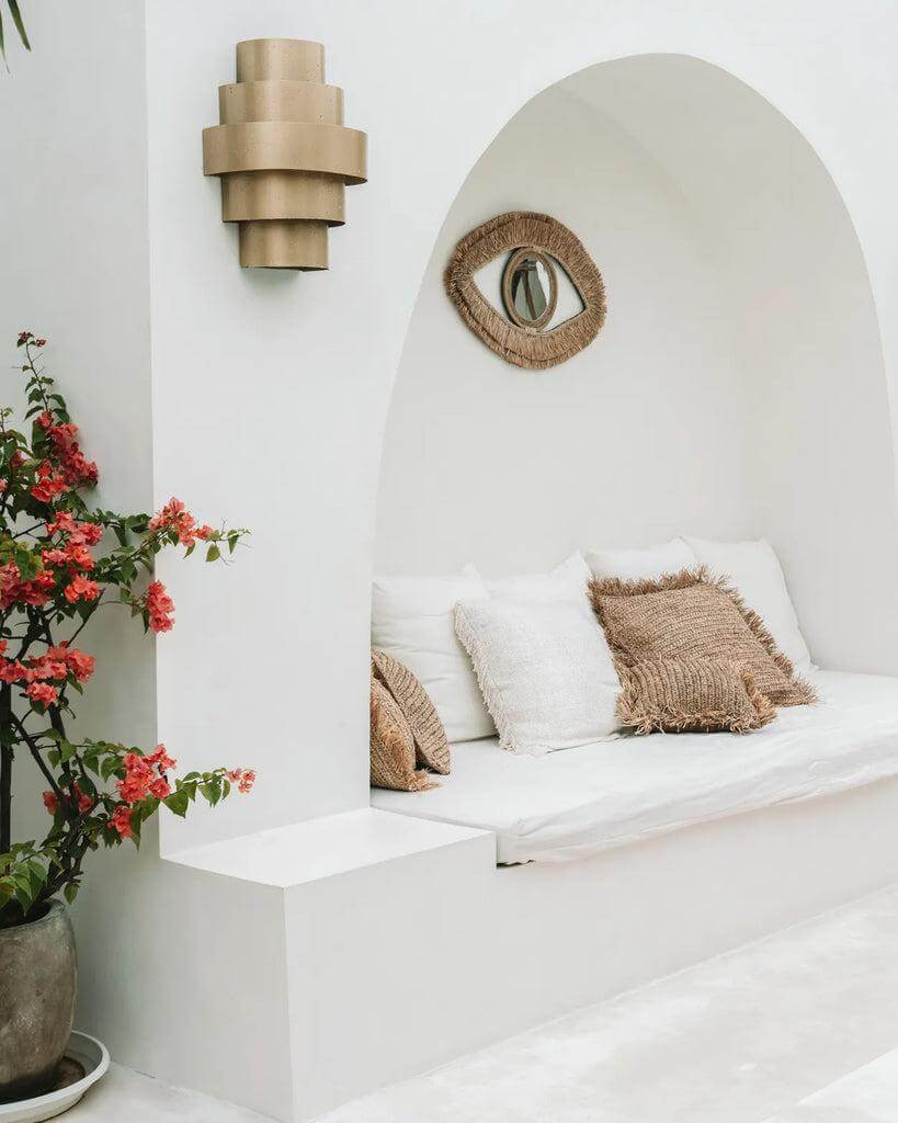 Gezellig boho zithoekje met Raffia Eye Mirror en zachte kussens, perfect voor een rustiek interieur.
