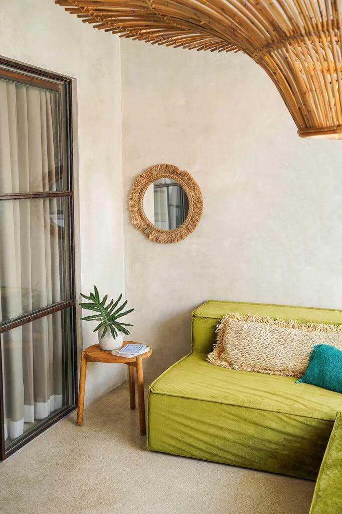 Stijlvolle Boho spiegel The Tahiti in een interieur met groene bank en natuurlijk decor in een gezellige zithoek.