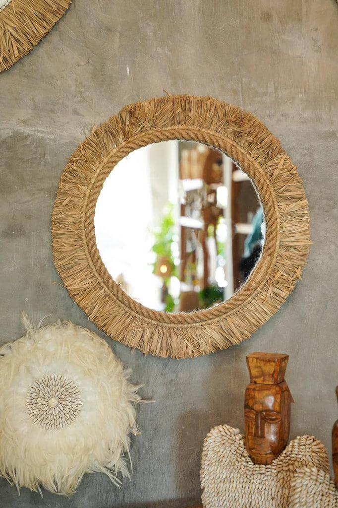 Indonesische raffia spiegel "The Tahiti" aan een muur met boho decor, perfect voor etnische en trendy interieurs.