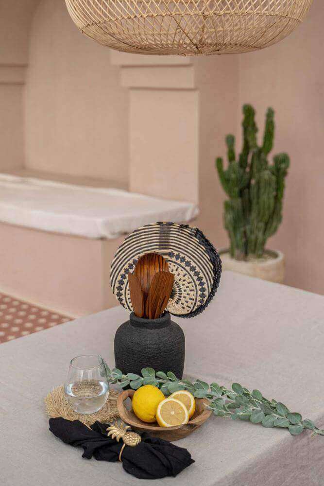 Chique zwarte Boho vaas met decoratieve elementen en citroenarrangement op tafel, perfect voor bohemian interieurinrichting.
