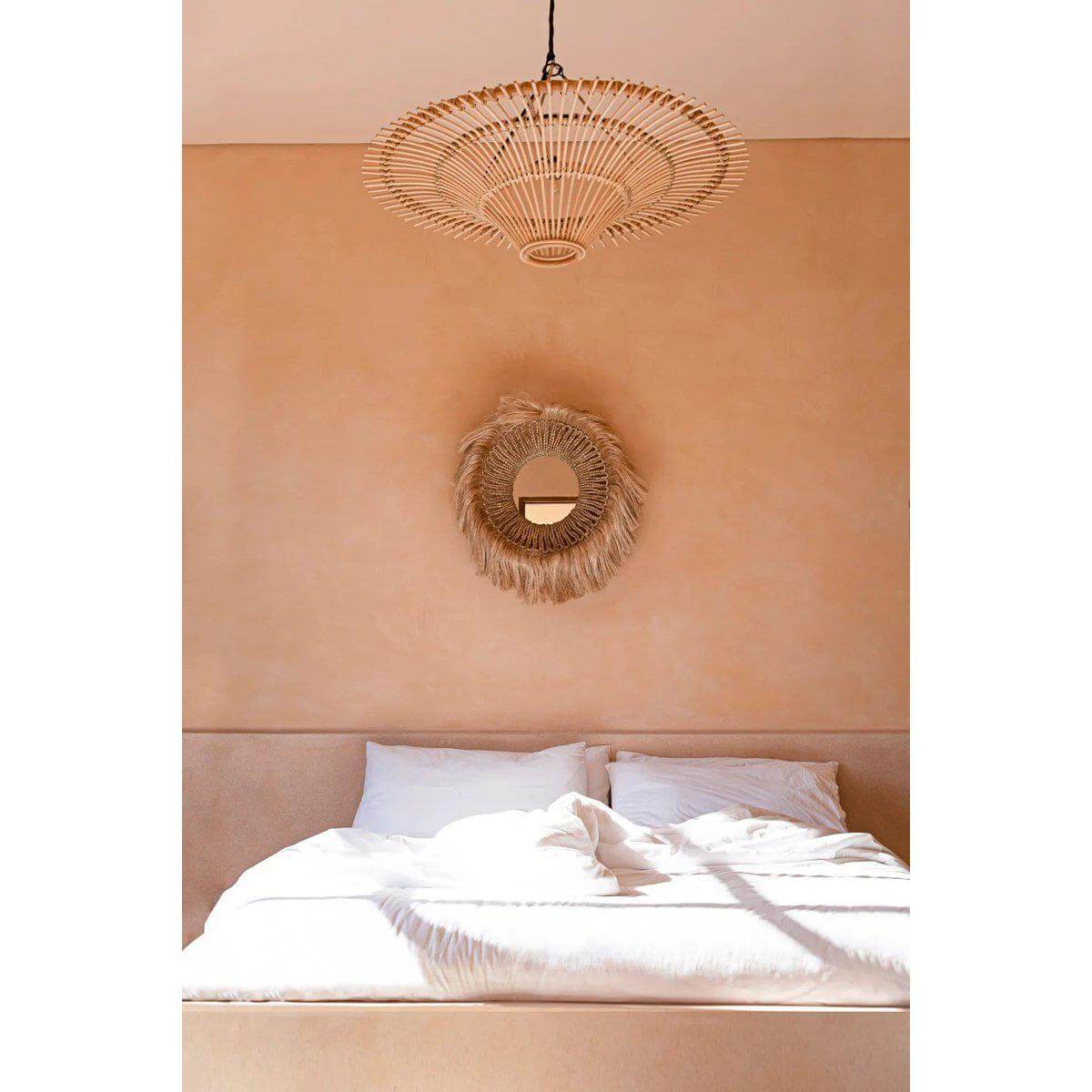 Handgemaakte Abaca Naturel spiegel aan de muur boven een beige bed in een elegante slaapkamer met natuurlijke tinten.