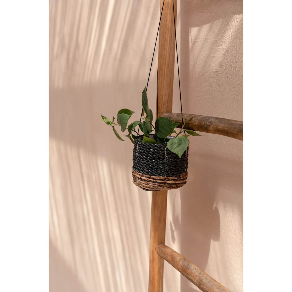 Bohemian round hanging basket made of banana leaf and seagrass, perfect for indoor plants, displayed on a wooden ladder.