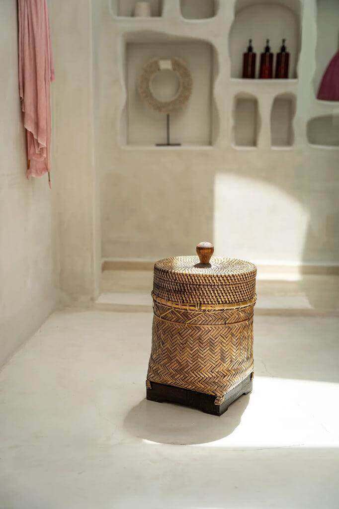 Rustieke badkamer mand van handgevlochten rotan in natuurlijke bruine tinten met koloniale charme en functionaliteit.