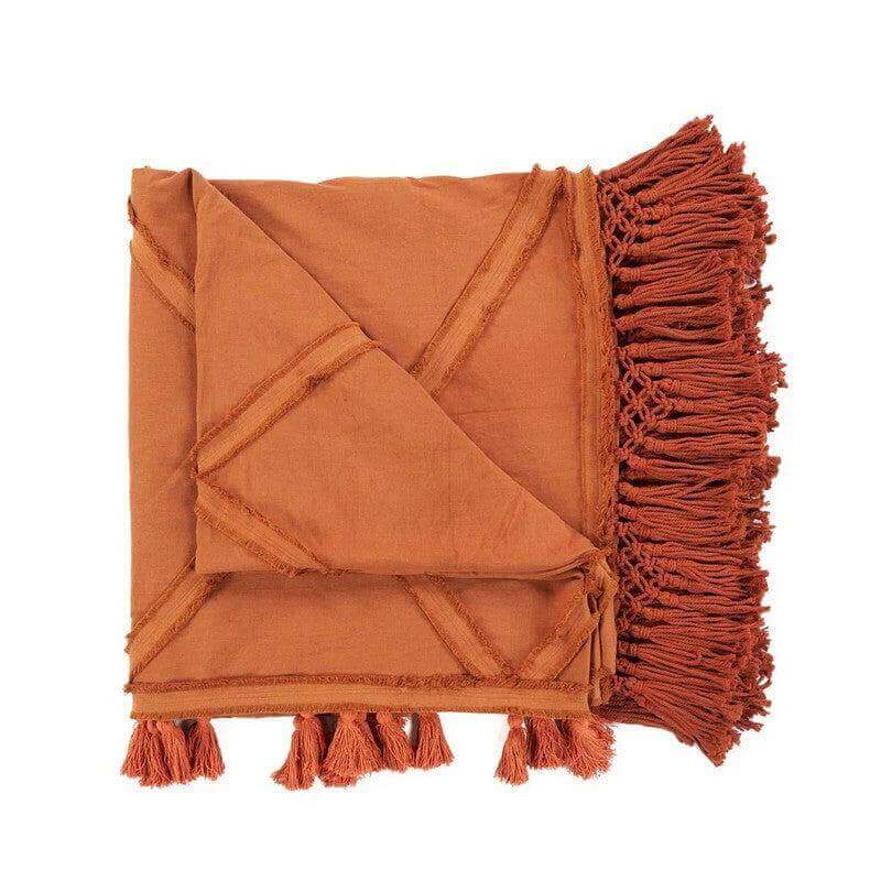 De Berber-bedsprei in terracotta kleur, weelderige franjes, luxe en warmte voor elke kamerinnals de woestijnzon.