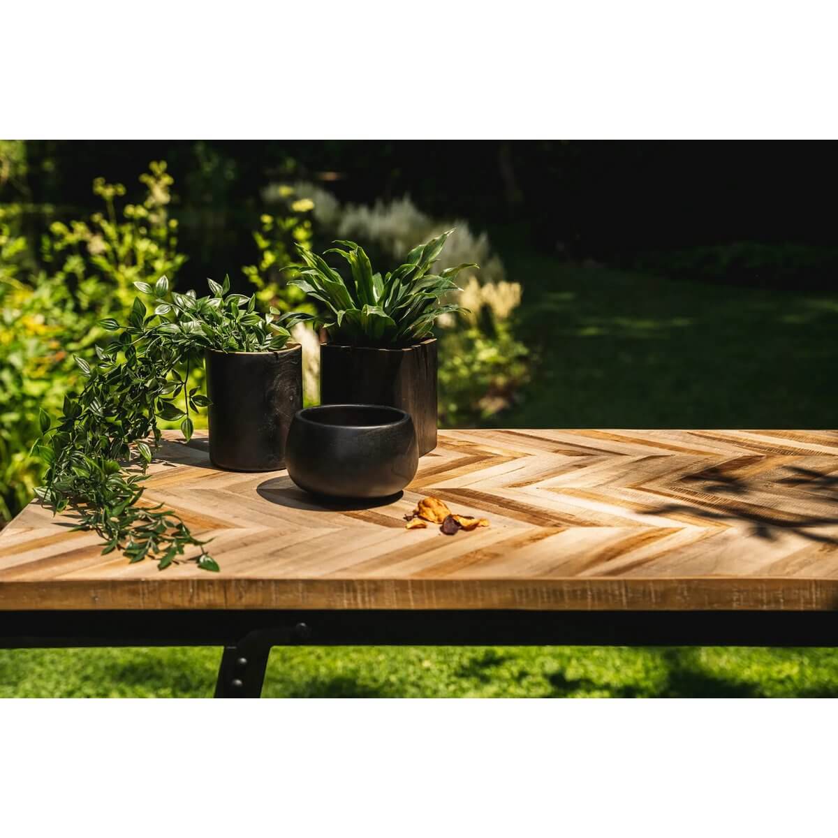 De Bondi Black Bowl in a garden setting on a wooden table, surrounded by lush greenery, perfect for bohemian decor.