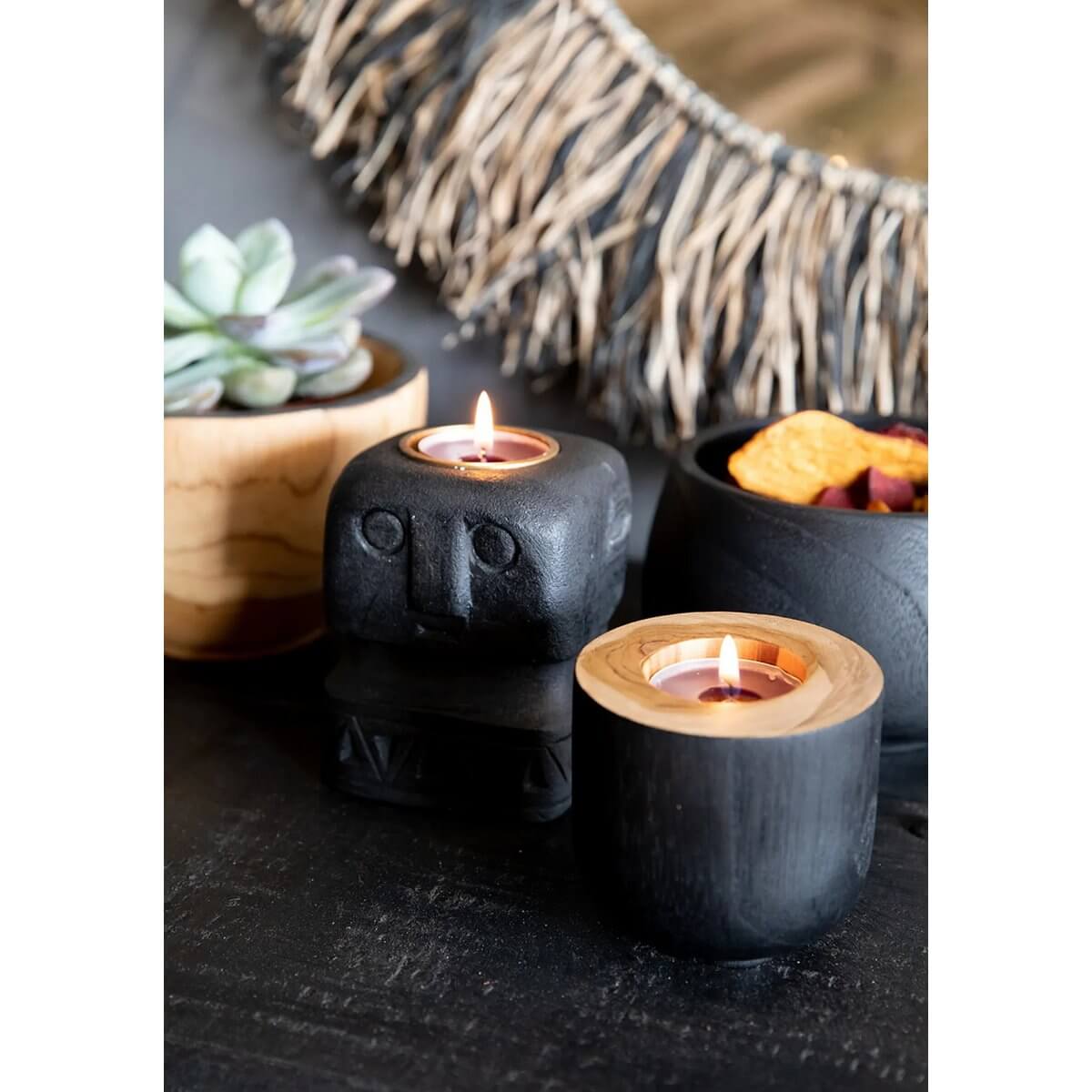 Cozy bohemian decor with candles, black teakhouten bowls, and a rustic mirror, perfect for a stylish and multifunctional interior setup.