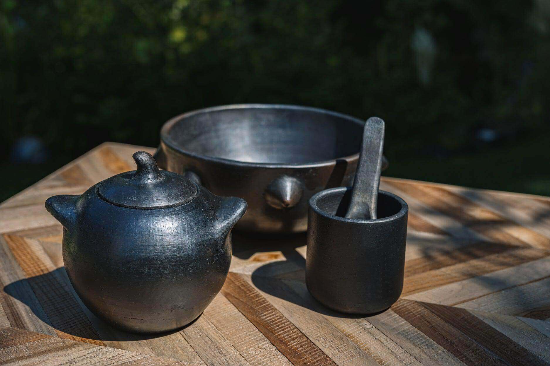 Zwart-gebrande serviescollectie inclusief beker, kom en theepot op houten tafel. Perfect voor kleurrijke, Insta-licious maaltijden.