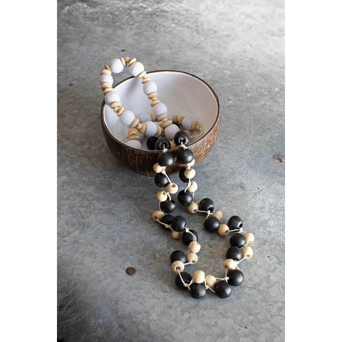 De Canggu ketting in natuurlijk zwart, met bohemian houten kralen in een kokoskom, benadrukt tijdloze esthetiek en lichtgewicht comfort.
