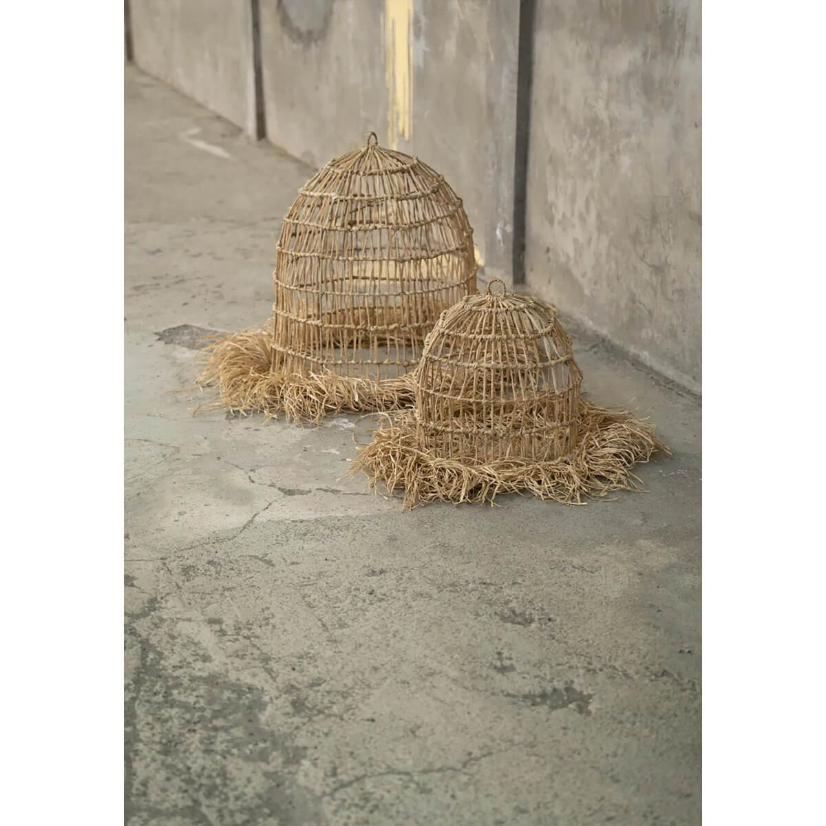 Bohemian Casita-hangers in natural mendonggras on concrete floor, adding a tropical vibe with fringes and unique light patterns.