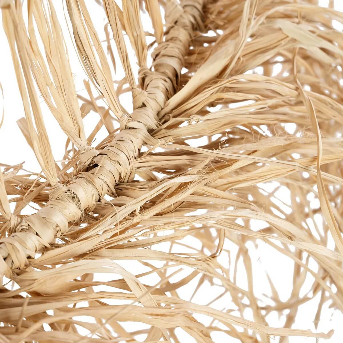 Close-up of De Casita-hanger handcrafted from natural mendong grass, featuring bohemian fringes for unique light patterns.