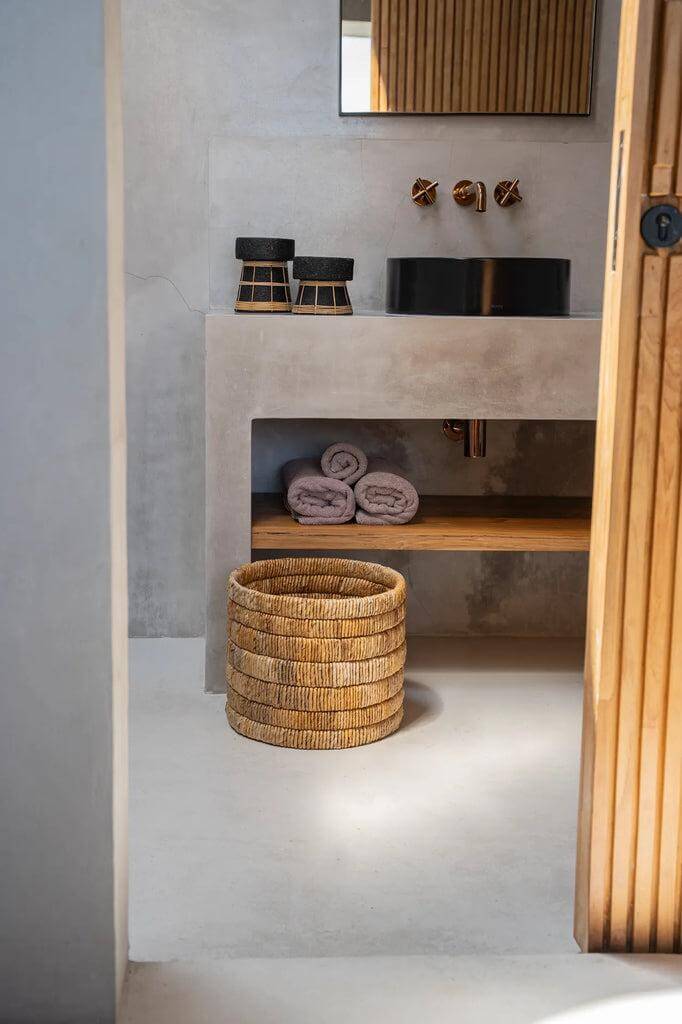 Handgeweven De Chuma Mand in moderne badkamer met houten accenten, gemaakt van bananenblad met prachtig patroon en veelzijdig ontwerp.