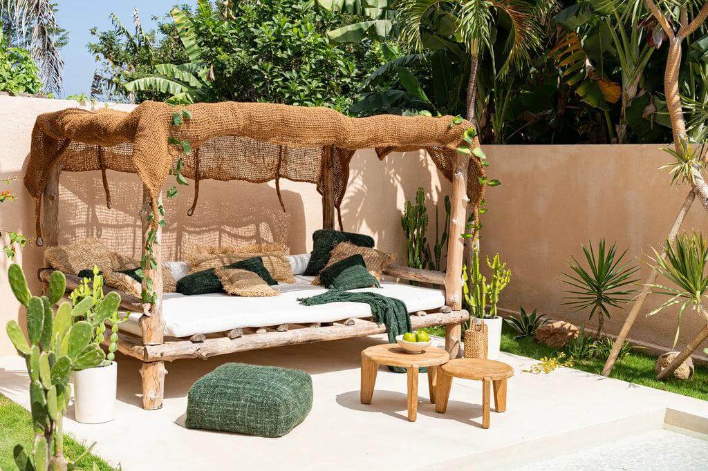 Alt Tag: Tropisch tuinbed met natuurlijke elementen en Coco Shade overkapping in zonnige buitenruimte omringd door groen.