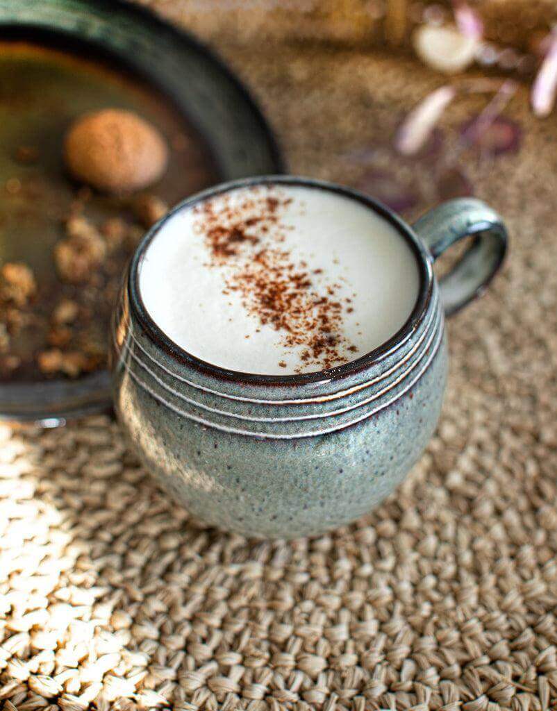 Rustieke aardewerken mok met koffie en kaneel op geweven tafelblad, perfect voor brunches en diners. Vaatwasserbestendig aardewerk.