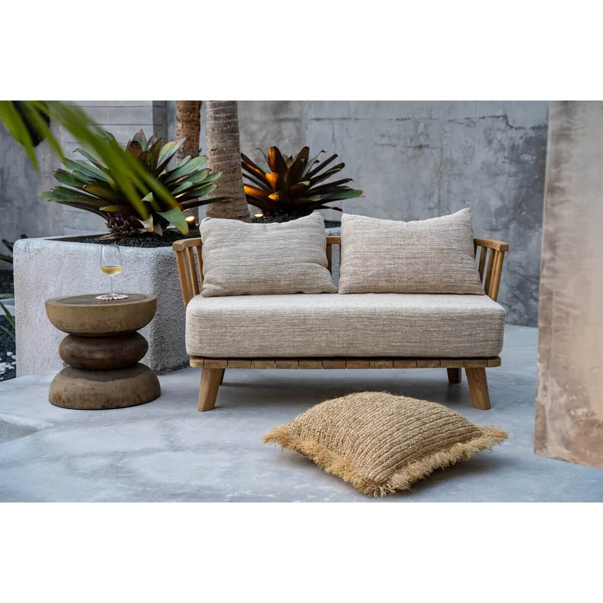Cozy bohemian outdoor setting with a woven sofa, spiral side table, and rustic cushion, perfect for a relaxing patio retreat.