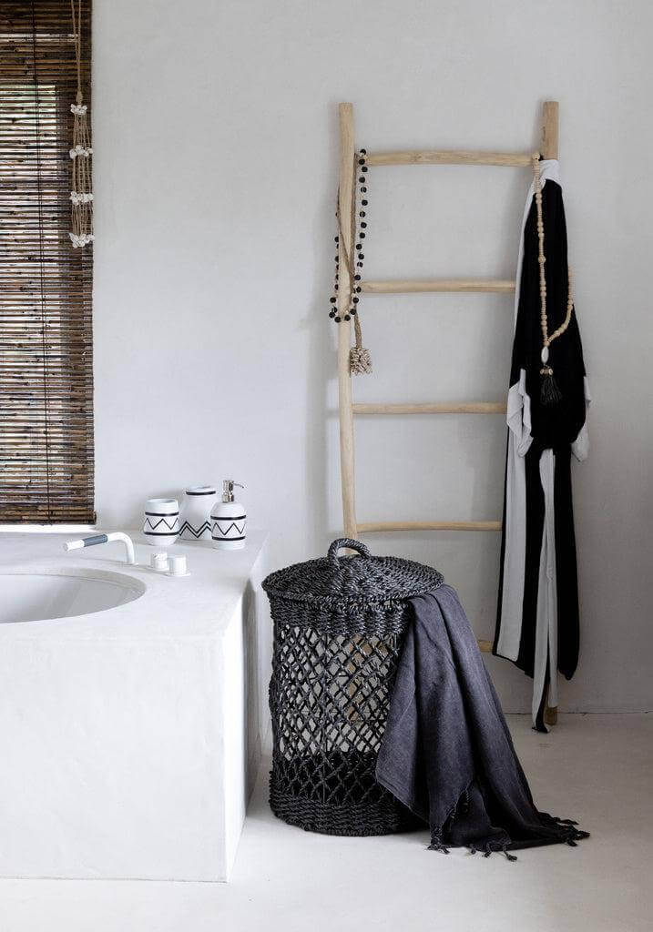 Moderne badkamer met zwart gevlochten wasmand en houten ladder decor.