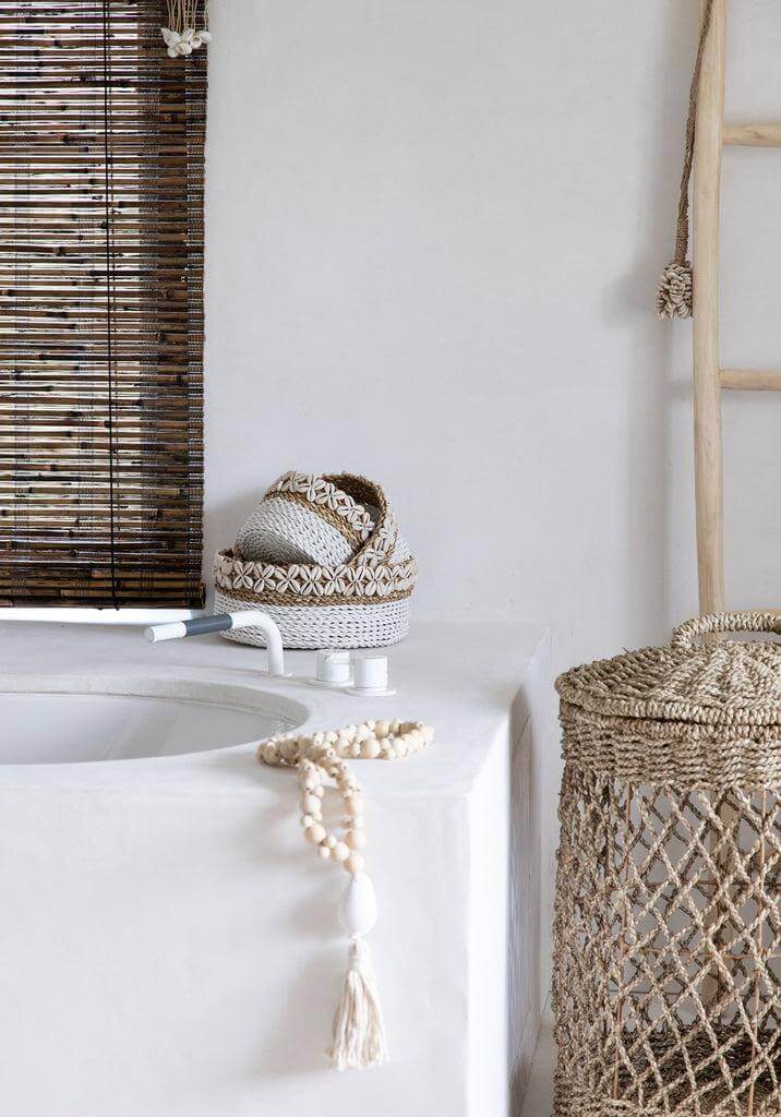 Natuurlijke interieurdecoratie met schelpenhanger en zeegrasmand in stijlvolle bohemian badkamer.
