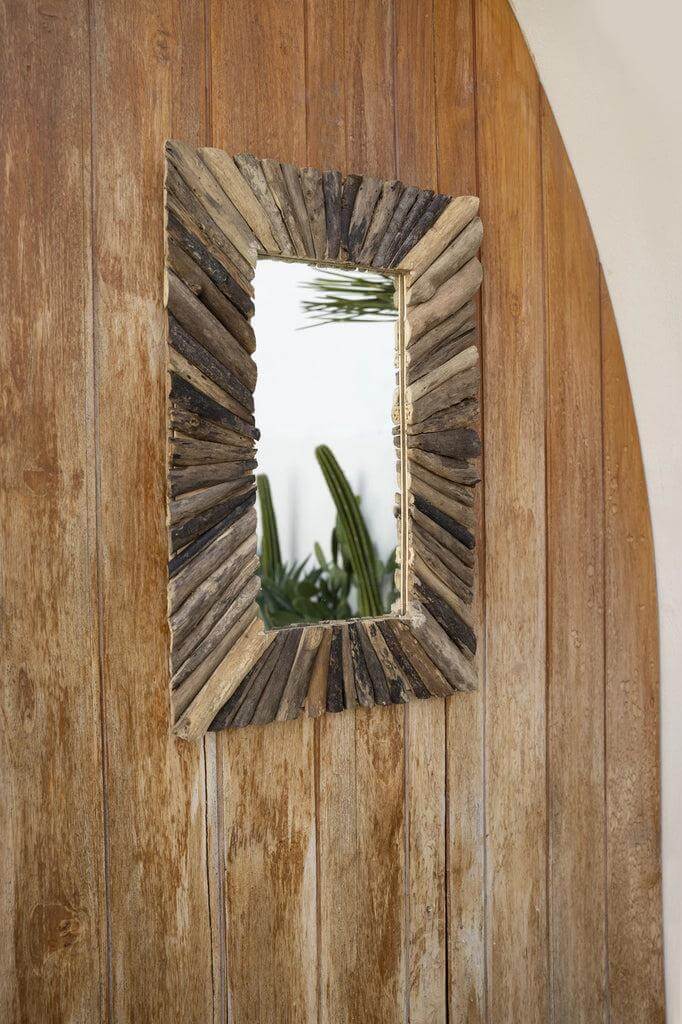 Rechthoekige spiegel met natuurlijke drijfhouten lijst tegen houten muur, decoratief en uniek design.