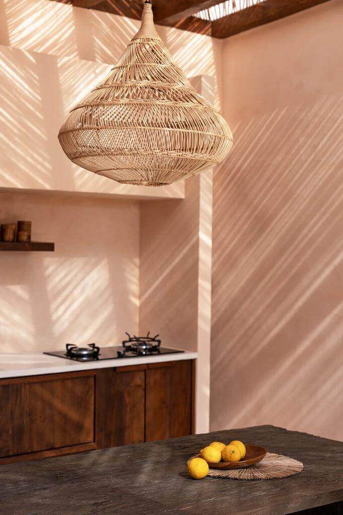Rotan hanglamp in druppelvorm verlicht keuken met natuurlijke sfeer.
