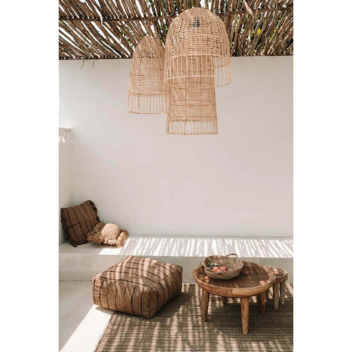 Stijlvolle kooivormige rotan hanglampen in een serene woonkamer met natuurlijke elementen en een strandachtige sfeer.