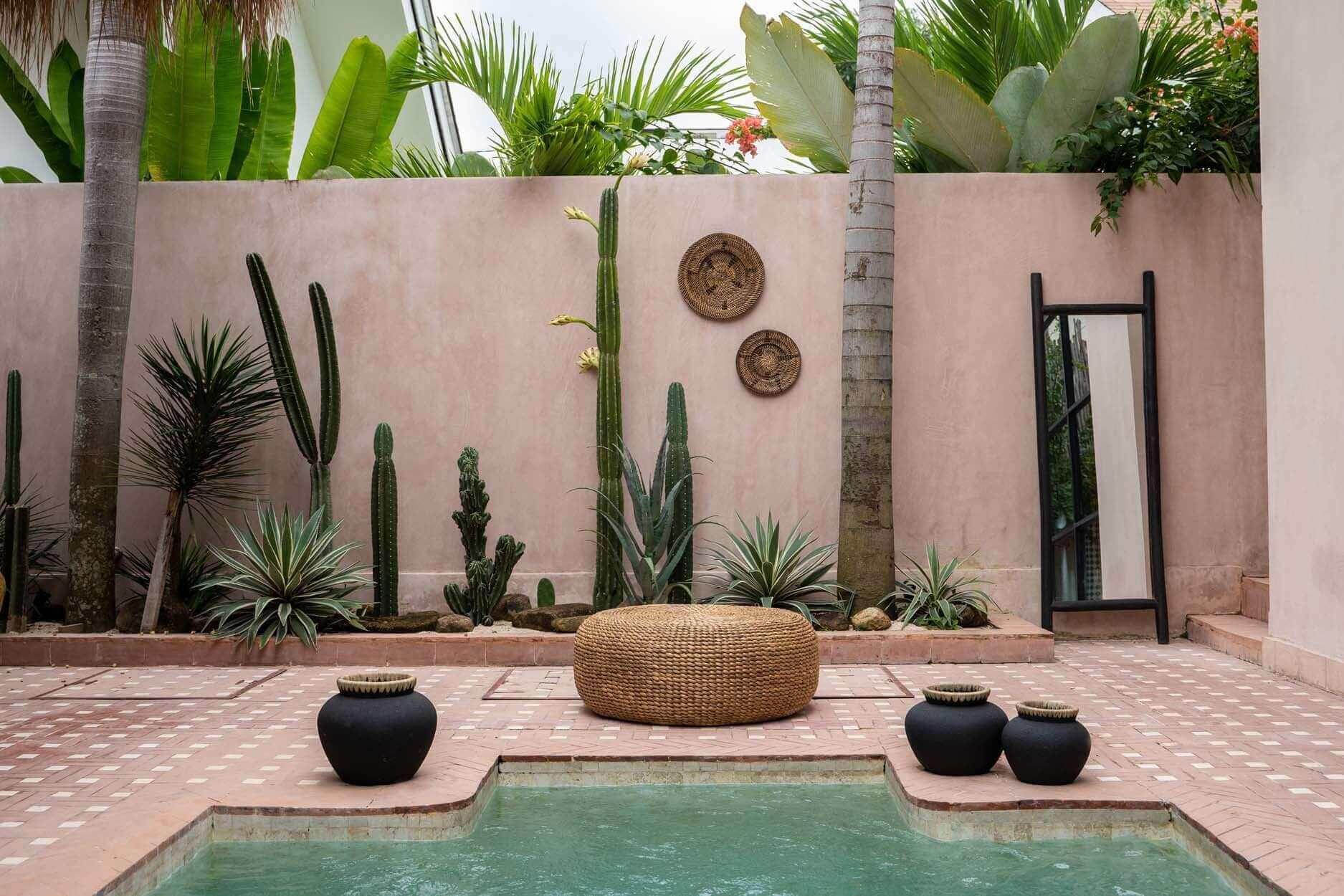 Stijlvolle boho tuin met De Hyacinth Poef als veelzijdig meubel, omgeven door cactussen en zwembad, voor een unieke uitstraling.