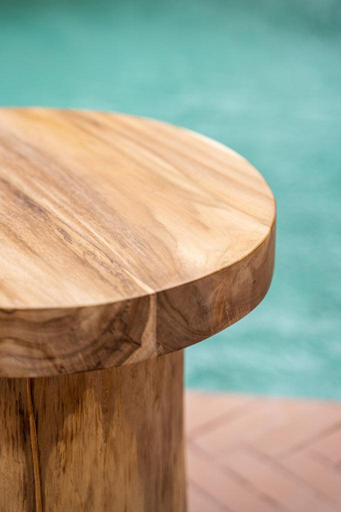 De Inti bijzettafel van teakhout bij een zwembad, duurzaam en natuurlijk design voor binnen- of overdekt buitengebruik.