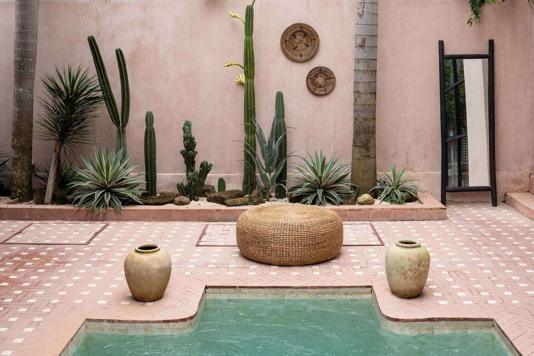 De Island Dressing Spiegel Zwart naast zwembad met decoratieve cactussen en potten in een serene tuinomgeving.