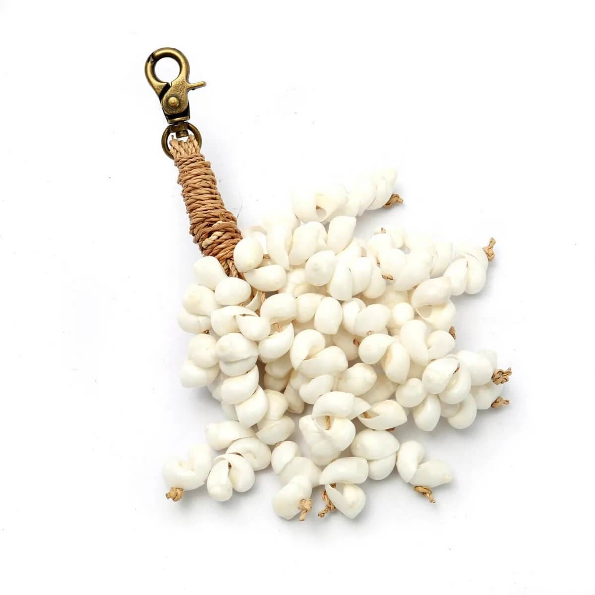 Bohemian De Kai shell keychain with white cowrie shells and cotton tassel, exuding coastal elegance and charm.