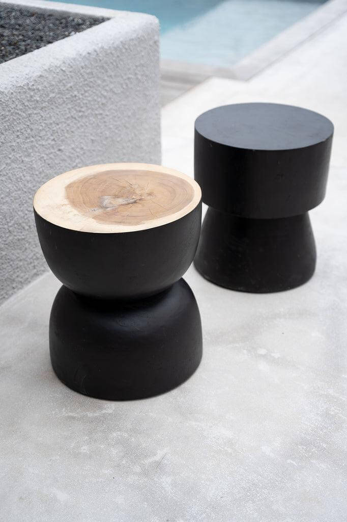 Twee zwarte en natuurlijke houten Karbun krukken bij een zwembad, stijlvol als kruk, bijzettafel of nachtkastje in interieur.