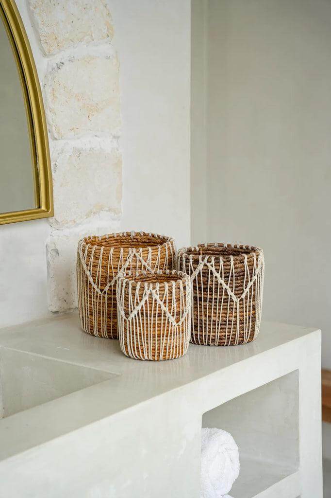 Drie handgemaakte macramé manden van bananenblad en katoen in natuurlijke tinten op een moderne kast.