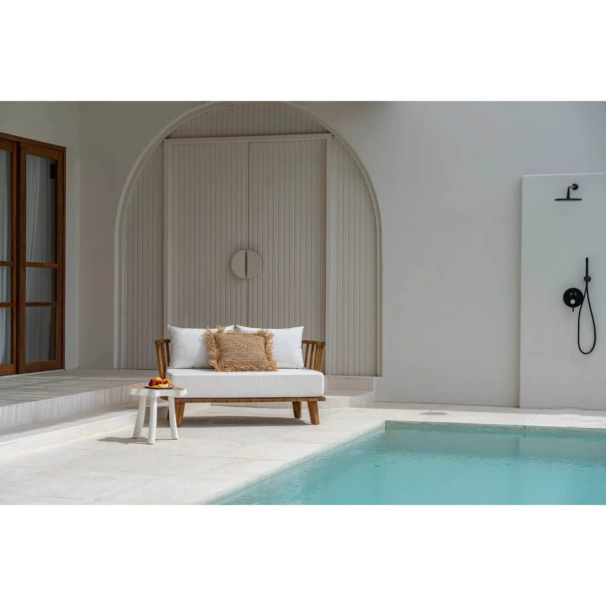Bohemian style outdoor loveseat by the pool, made from reclaimed teak with water-repellent cushions, offering chic comfort.