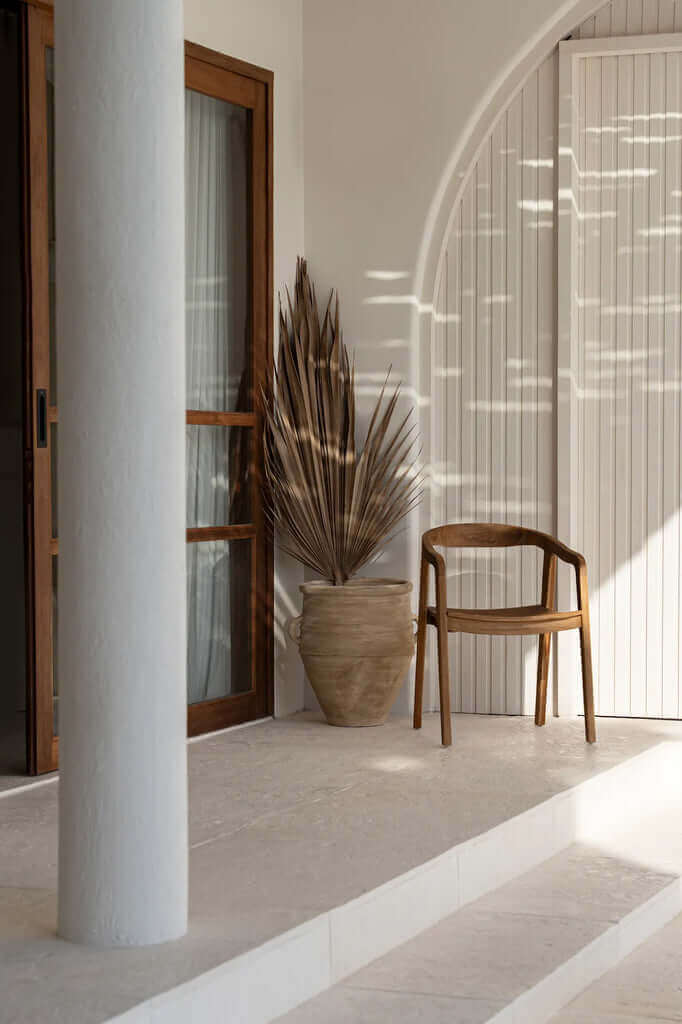 Nihi Oka stoel in minimalistische buitenruimte met teakhouten design en tijdloos karakter, ideaal voor zowel binnen als buiten.