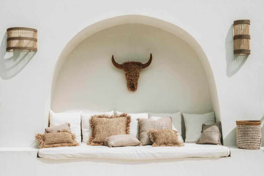Boho zithoek met beige kussens, zachte katoenen hoezen, en een rustieke stierschedel decoratie, perfect voor een chique inrichting.