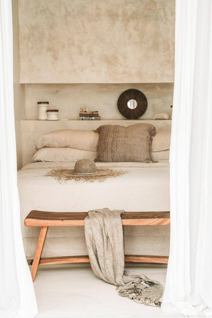 Stijlvolle slaapkamer met beige Oh My Gee kussenhoes, boho inrichting en houten bankje. Voeg textuur toe aan uw interieur.
