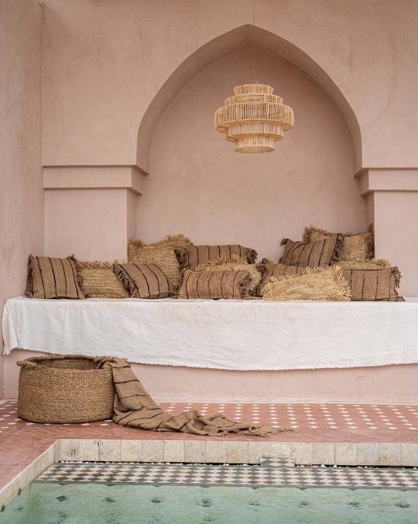 Gezellige loungehoek met boho kussens en beige decor rondom een stijlvol zwembad.