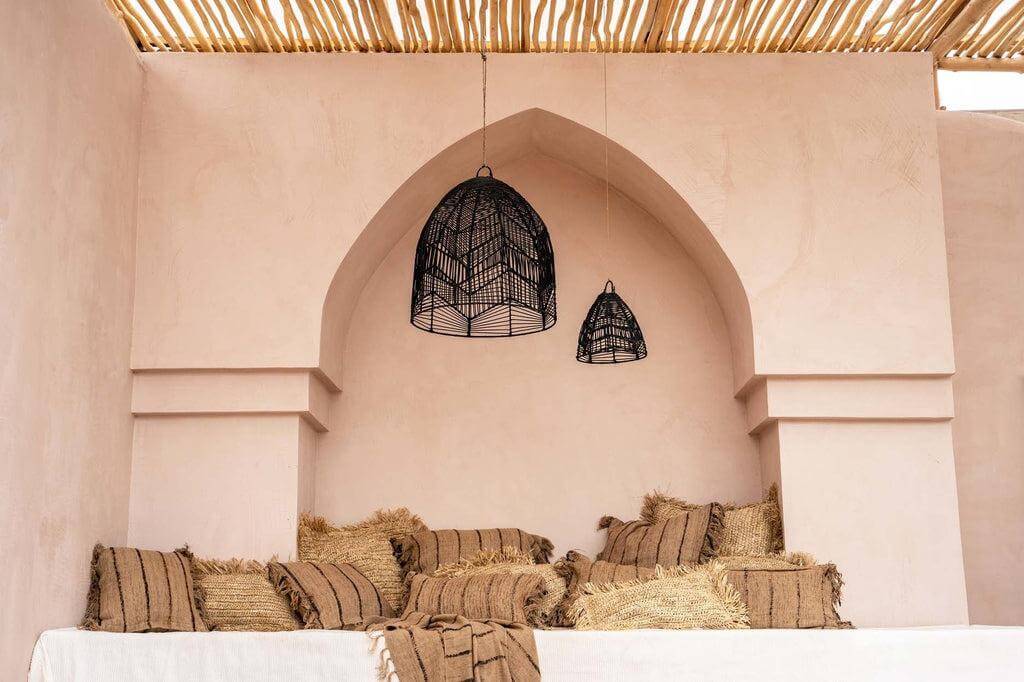 Stijlvolle beige zithoek met boho-stijl kussens en zwarte hanglampen voor een rustiek interieurdesign.