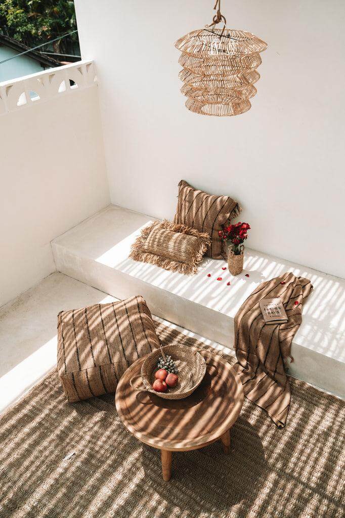 Boho zithoek met beige en zwarte De Oh My Gee kussenhoes in een zonnige patio setting.