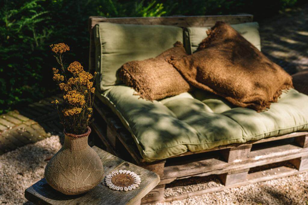Bruine kussenhoes op boho-stijl palletbank in tuin, voegt chique en textuur toe aan buiteninrichting, geen binnenkussen inbegrepen.