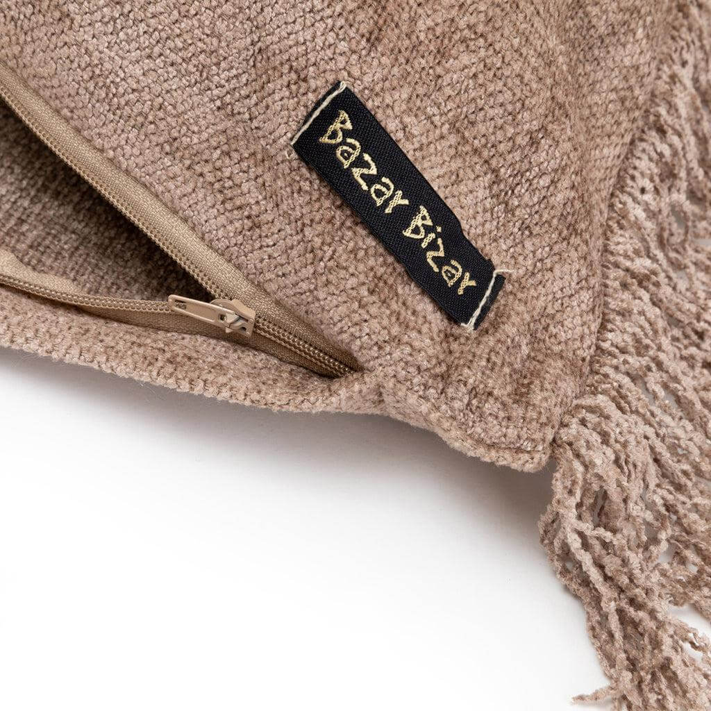 Detail van de Bazar Bizar kussenhoes met franjes, rits en label, gemaakt van handgeweven textiel voor boho interieurstijl.
