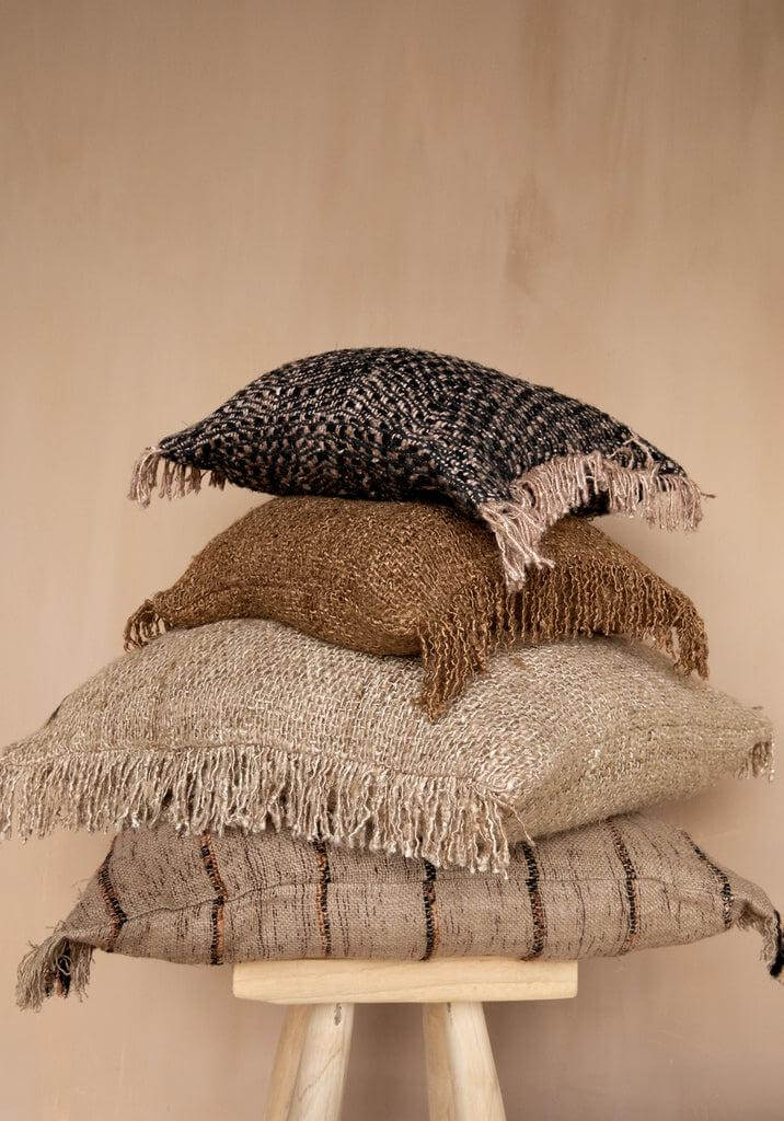Een stapel van vier boho-chique kussenhoezen in aardetinten met franjes, perfecte aanvulling voor een stijlvol interieur of tuin.