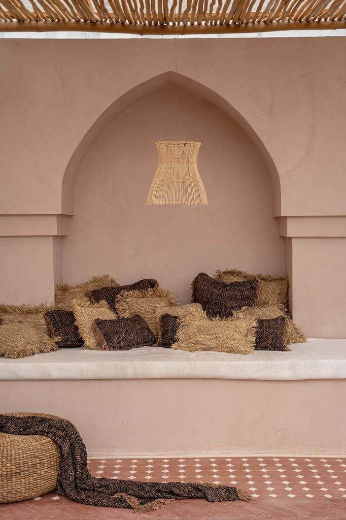 Knusse zithoek met kussens en boho-touch in natuurlijke tinten onder decoratief gewelf.