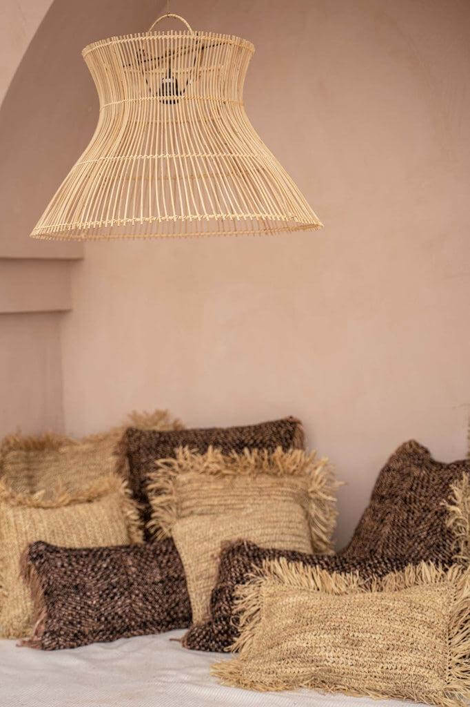 Alt Tag: Boho-chic zithoek met zwarte en koperen kussenhoezen, gezellige texturen en een rieten hanglamp