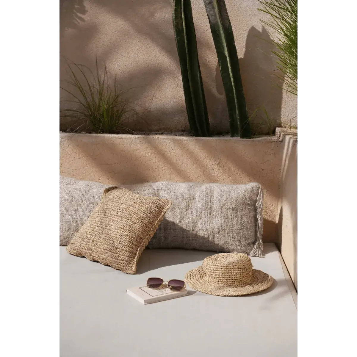 Bohemian Pantai-hoed van natuurlijk zeegras op een ligbed met kussen en zon, voor een stijlvolle stranduitstraling.