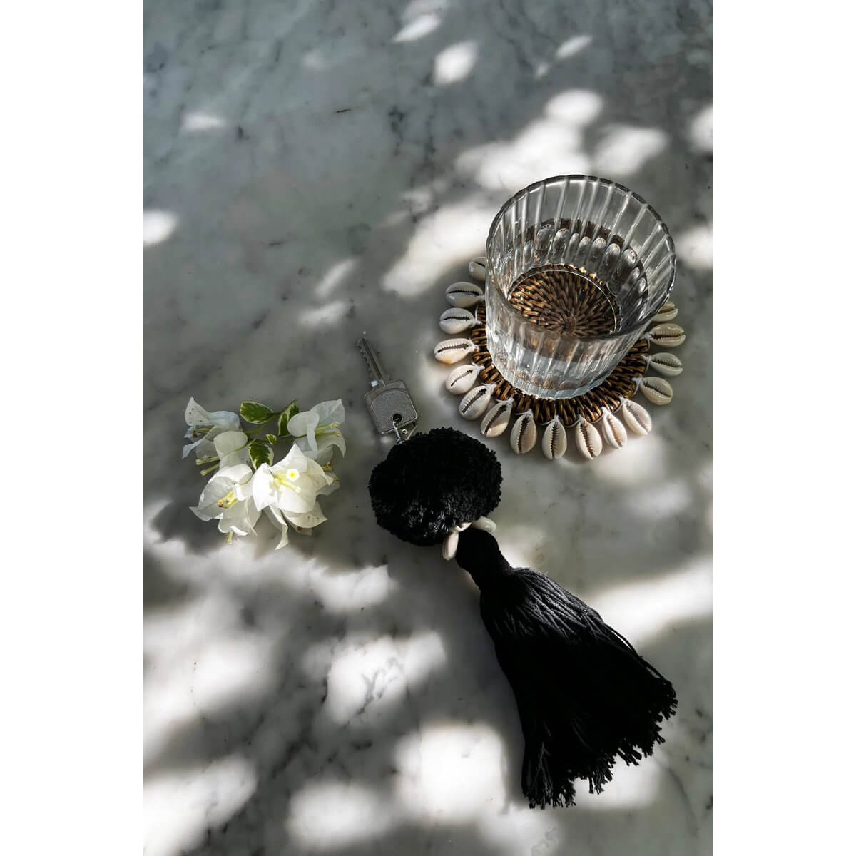 Chic Bohemian black pompom keychain styled on a marble surface with flowers and a decorative coaster.