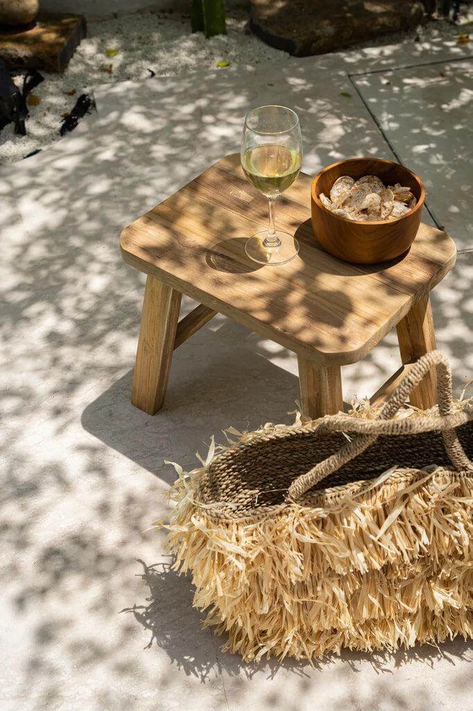 Houten De Quincy Kruk met glas wijn en snacks in de zon, ideaal als bijzettafel of nachtkastje, eco-vriendelijk ontwerp.