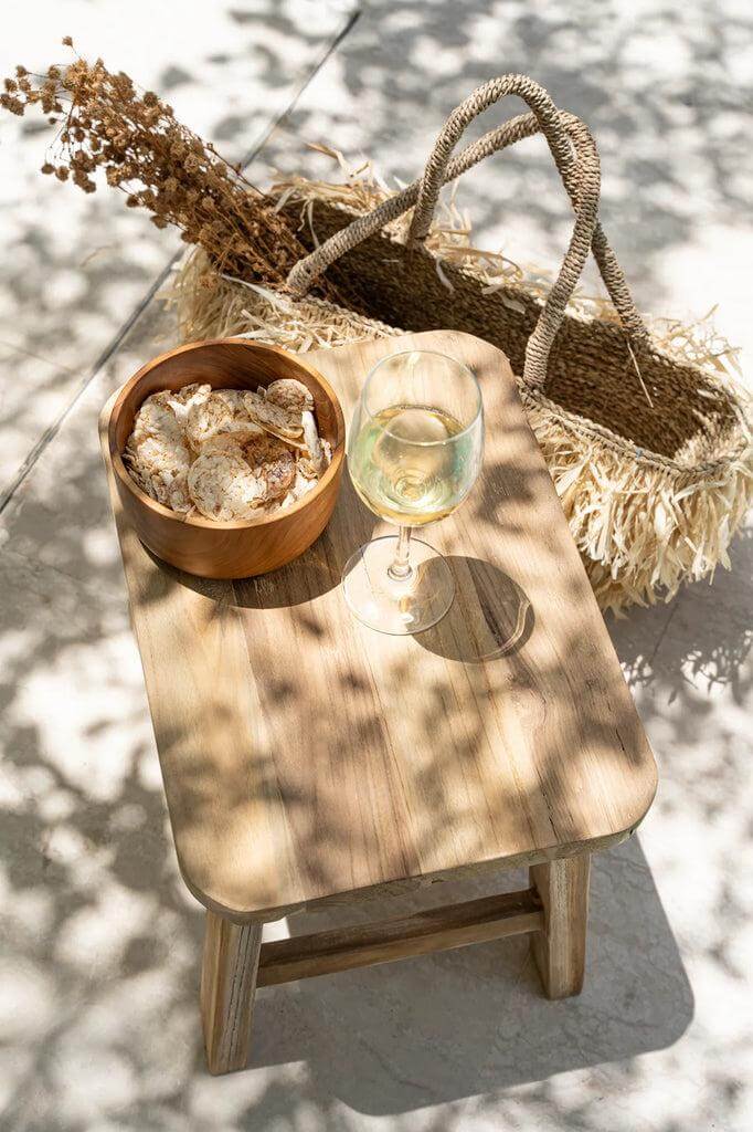 Stijlvolle De Quincy Kruk van gerecycled materiaal met decoratieve items en schaduw van bladeren, ideaal als bijzettafel of extra zitplaats.