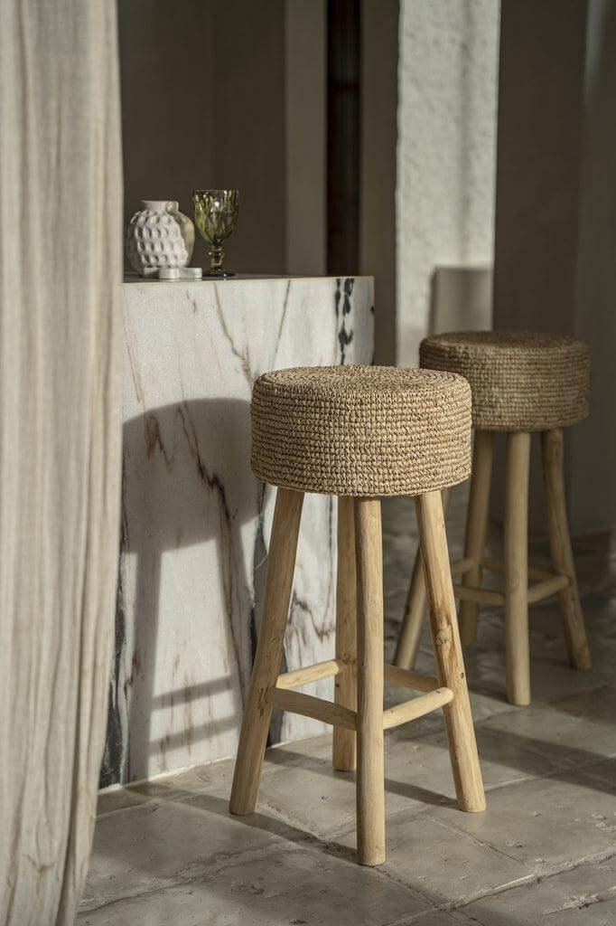 Natuurlijke raffia barstoelen met teakhouten poten in bohemian interieur bij marmeren keukenblad.