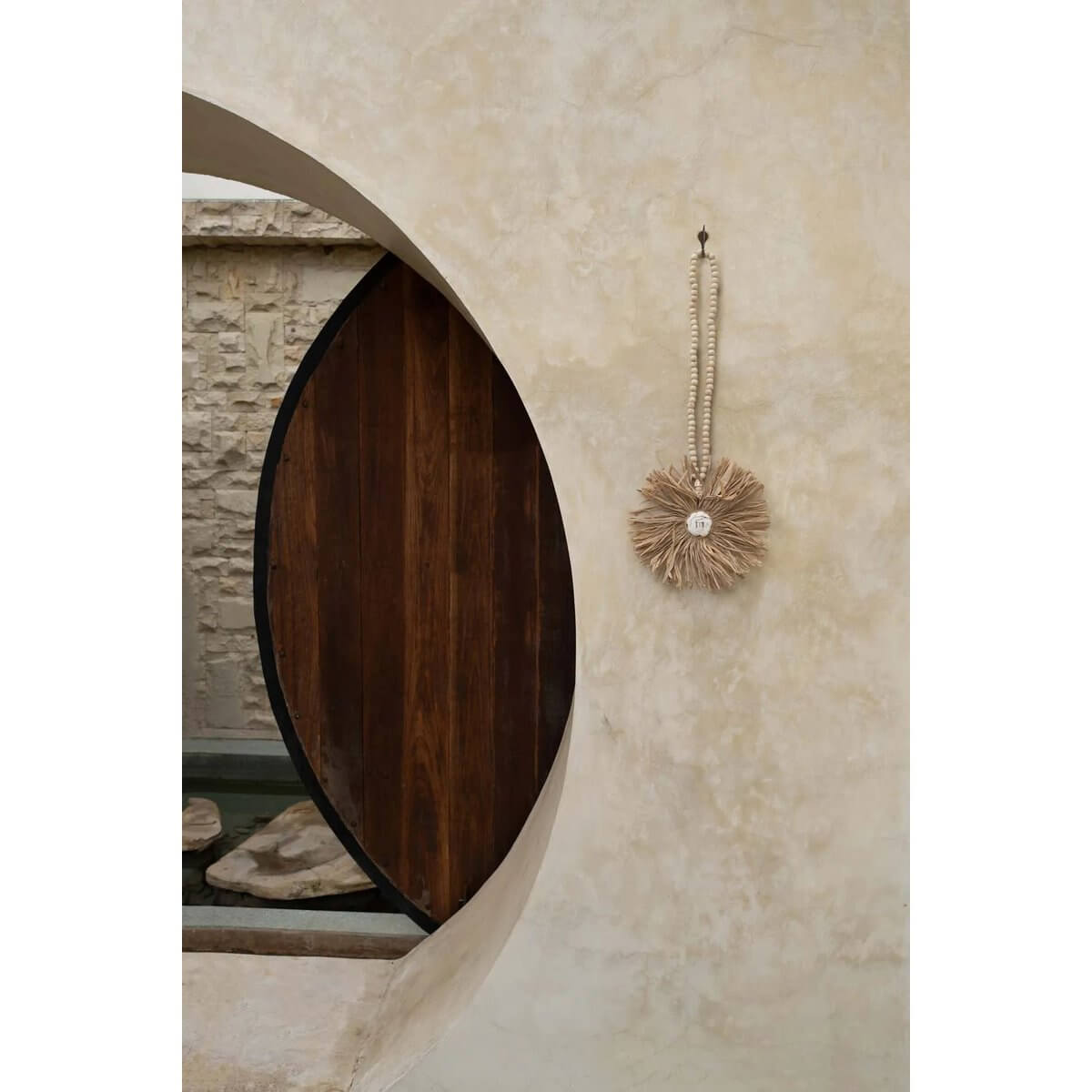 Bohemian-style raffia tassel with intricate design, draped elegantly on a rustic wall, adding natural charm to the decor.