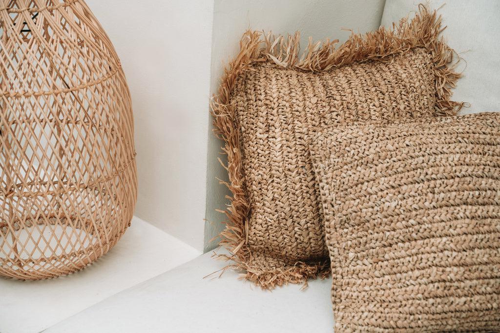 Rustieke raffia kussenhoezen op een bank, handgeweven in Indonesië voor een natuurlijke, boho uitstraling. Perfect voor interieurdecoratie.