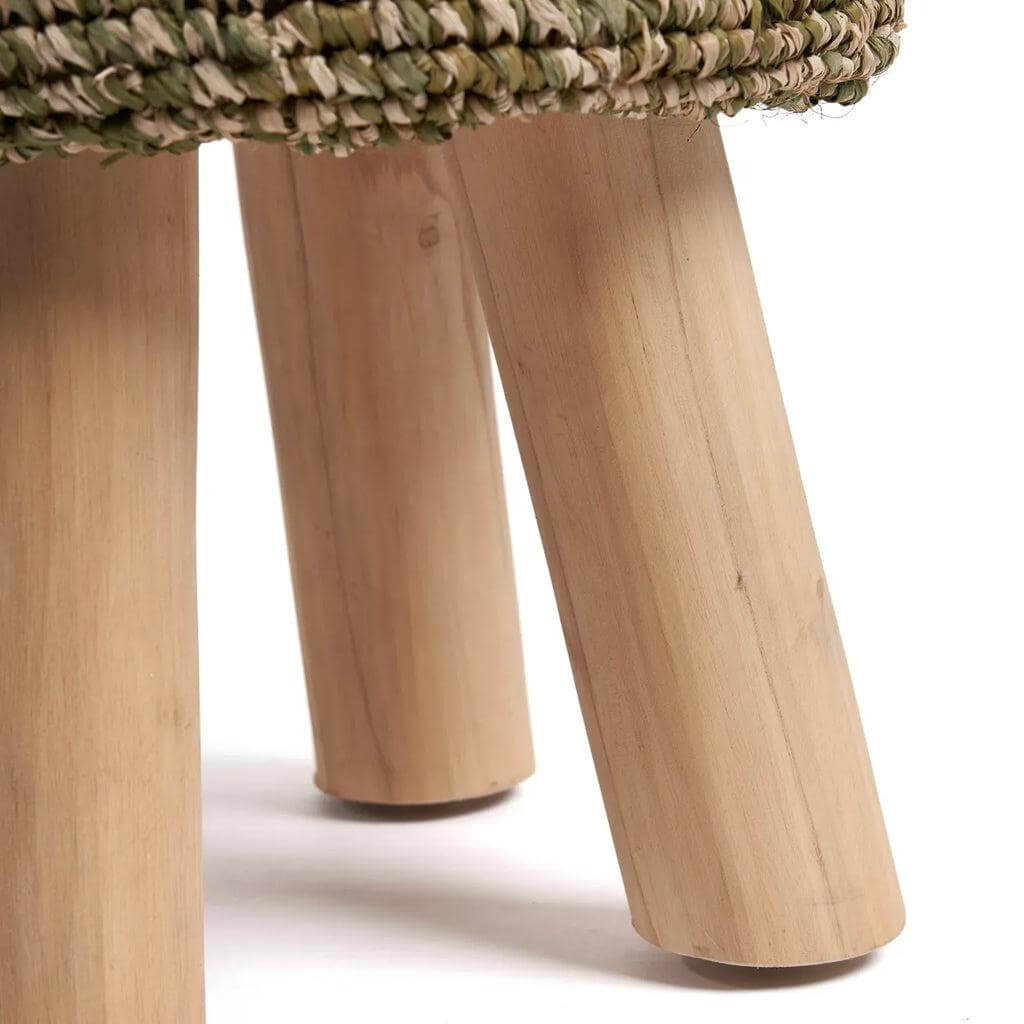 Detail van De Raffia Gevlochten Kruk in Jungle Groen, met stevige houten poten en natuurlijke vlechtstructuur.